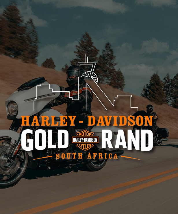 Harley-Davidson Gold Rand South Africa logo over a motorcyclist riding a white bike on a curving road with trees in the background
