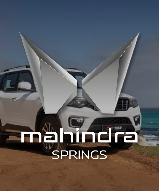 Brand banner for Mahindra Springs: silver geometric emblem above the text 'mahindra SPRINGS' with a white SUV on a beach.